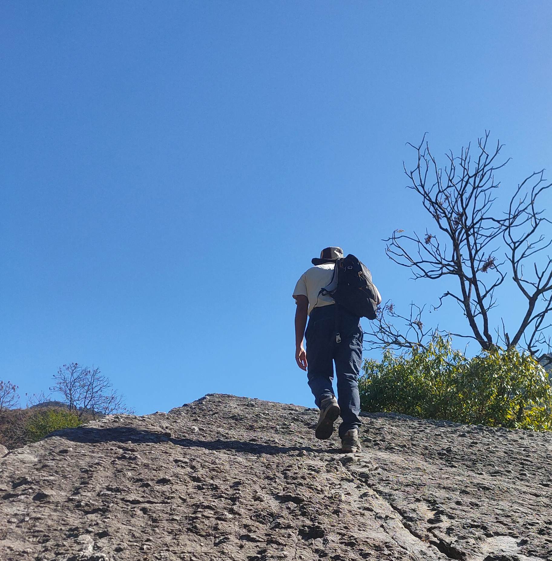 Solo hiker on a bare rock ridge under deep blue sky